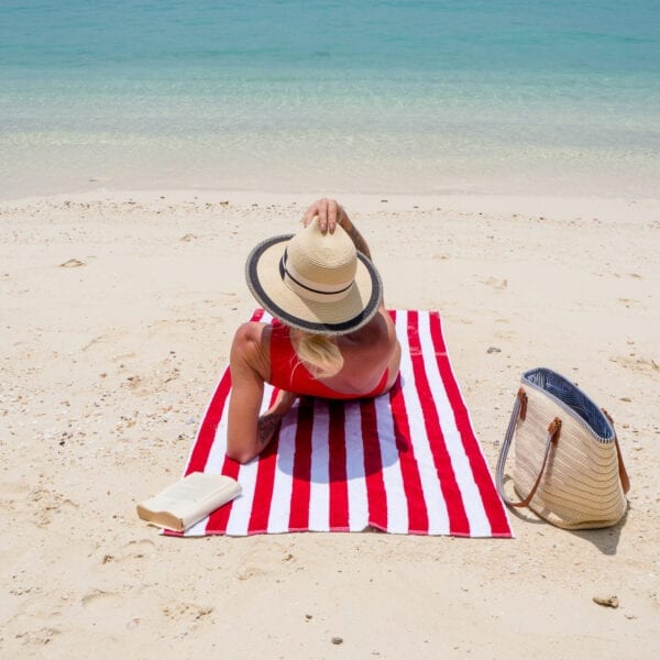 Woman laying on California Cabana Towels - Red on the beach