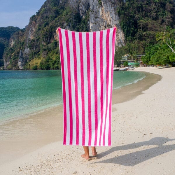 Woman holding California Cabana Towels - Pink while standing by the ocean