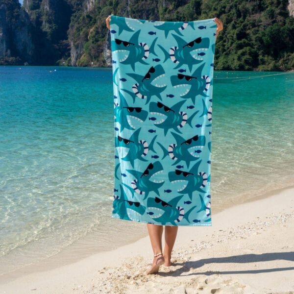 Woman holding Printed Beach Towel - Sharks with Glasses by the ocean